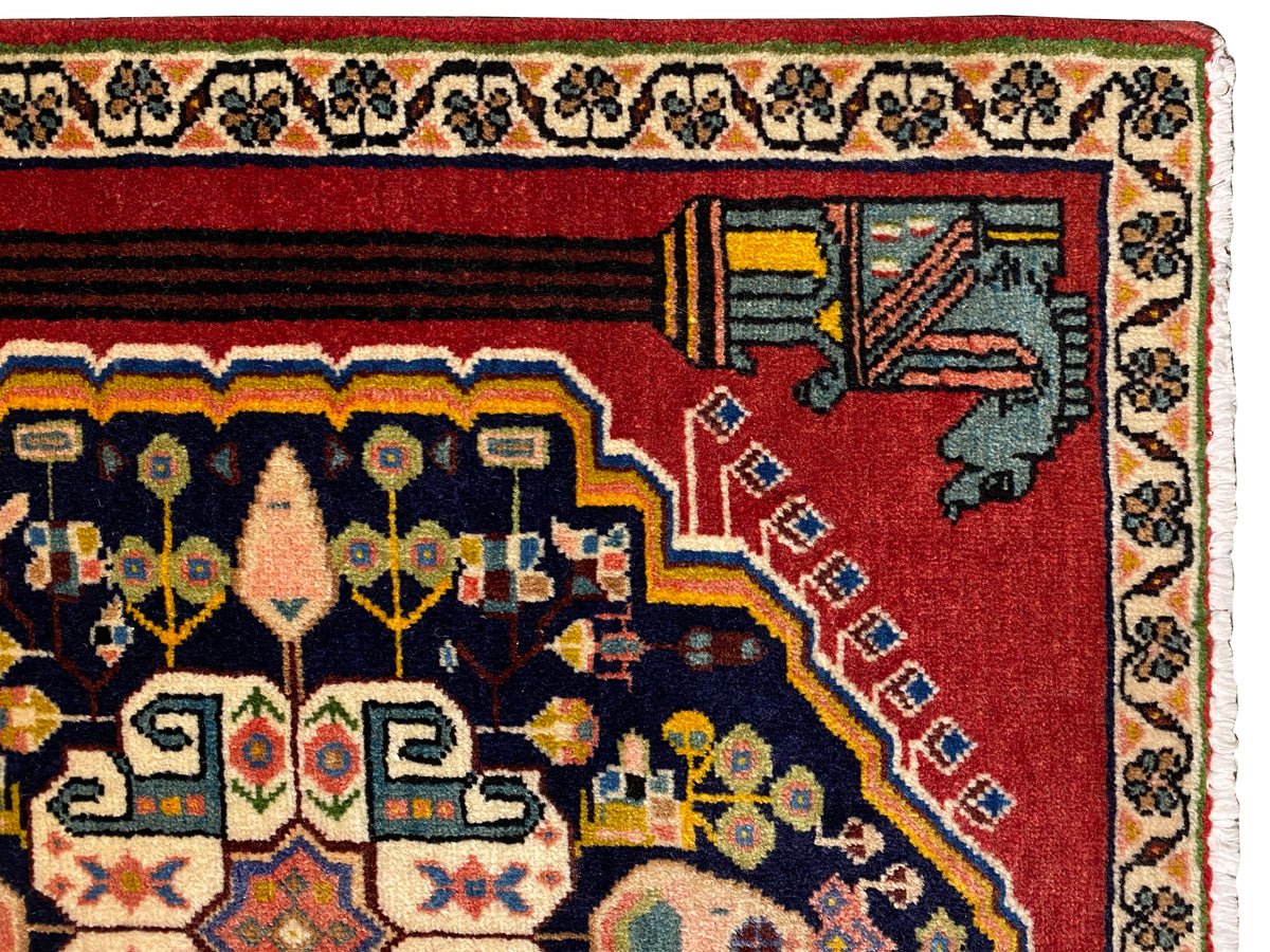 Vue rapprochée d’un tapis Poshti : bordure rouge avec motifs d’angle décoratifs et bandes ornementales