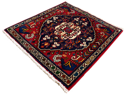 Tapis carré avec ornement coloré, surface bleu profond, motifs de bordure, franges