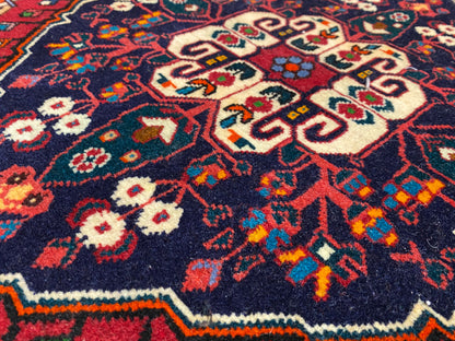 Gros plan du velours du tapis orné de motifs colorés en bleu, rouge, crème et vert