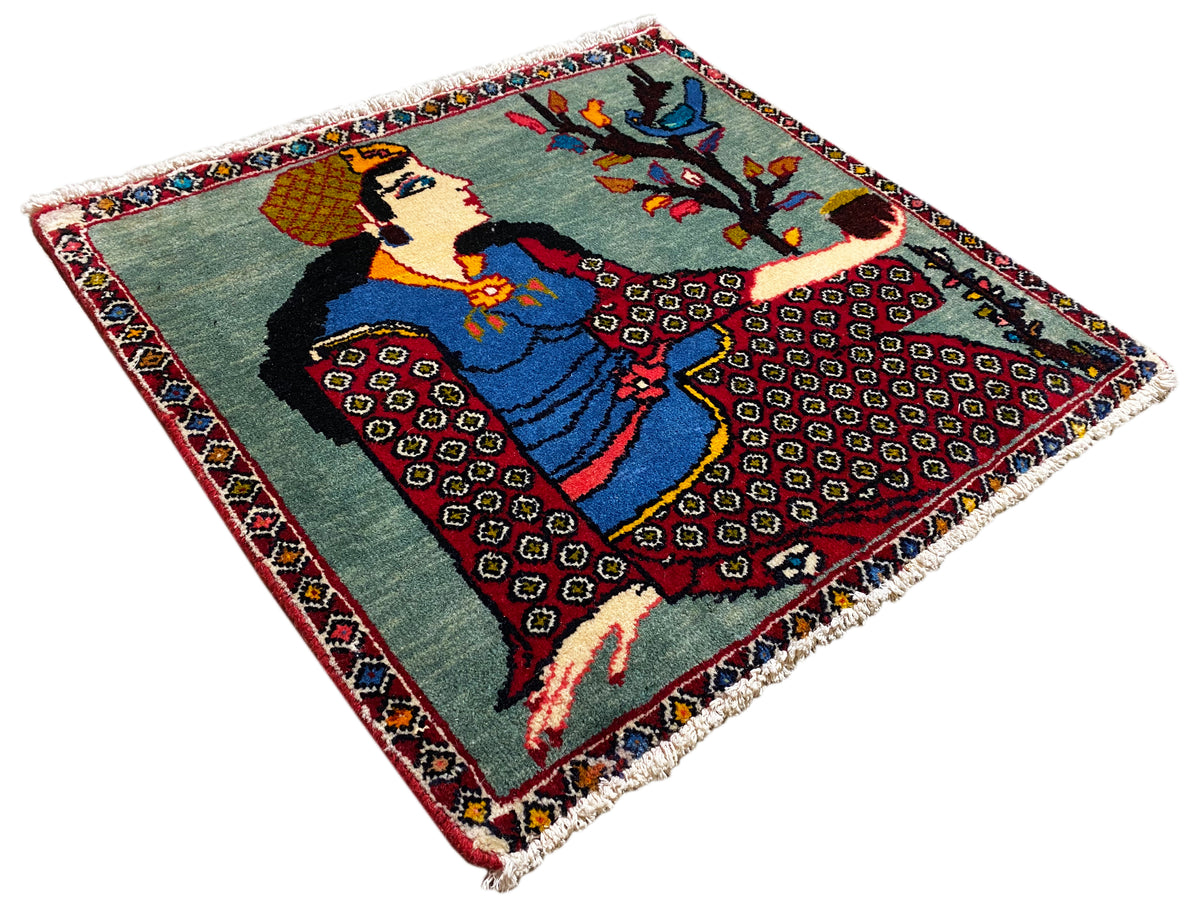 Tapis Poshti 68x63 cm vu en biais du dessus : motif figuratif avec arbre, bordure colorée, franges