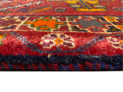 Gros plan du bord du tapis avec des poils rouges et une bordure multicolore