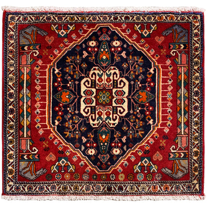 Tapis carré à fond rouge et motif central bleu foncé, avec des franges