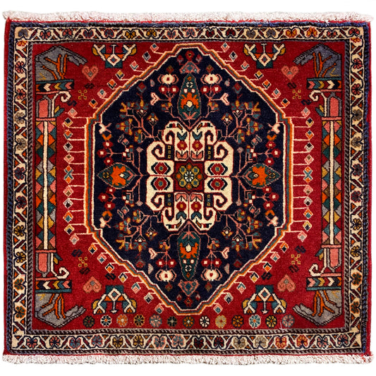 Tapis carré à fond rouge et motif central bleu foncé, avec des franges