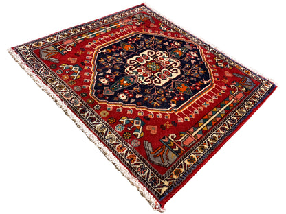 Tapis à fond rouge et médaillon central sombre, rectangulaire, bordé de franges
