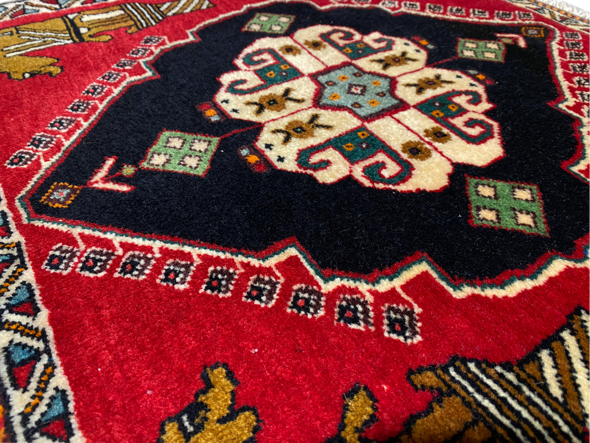 Tapis Poshti 63x55 cm : gros plan sur le médaillon central aux motifs rouges et noirs