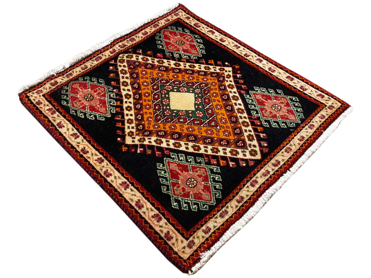 Tapis Poshti déployé en vue losange : fond noir, motifs orange et cases rouges/vertes
