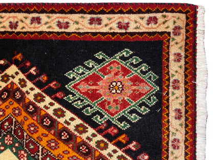 Gros plan d’un tapis Poshti : bordure texturée à franges et losange-médaillon rouge et vert