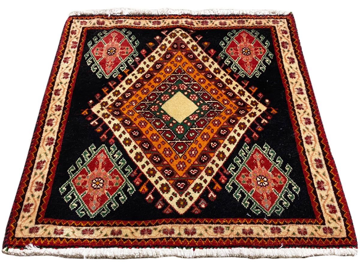Tapis Poshti carré à fond noir, composition centrale en losanges et bordure décorative périphérique