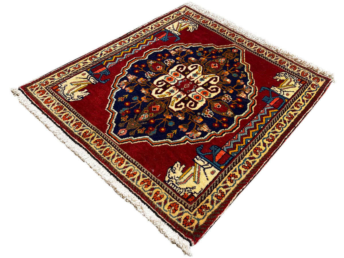 Tapis à fond rouge, motif central bleu foncé, bordures ornementales beiges et franges
