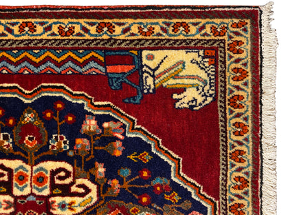 Vue détaillée : motif de tapis rouge et bleu foncé avec des éléments beiges représentant des animaux/des personnages