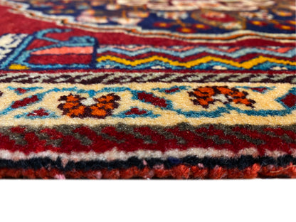 Détail rapproché du tapis : bordure colorée, ornements multicolores et structure à poils épais