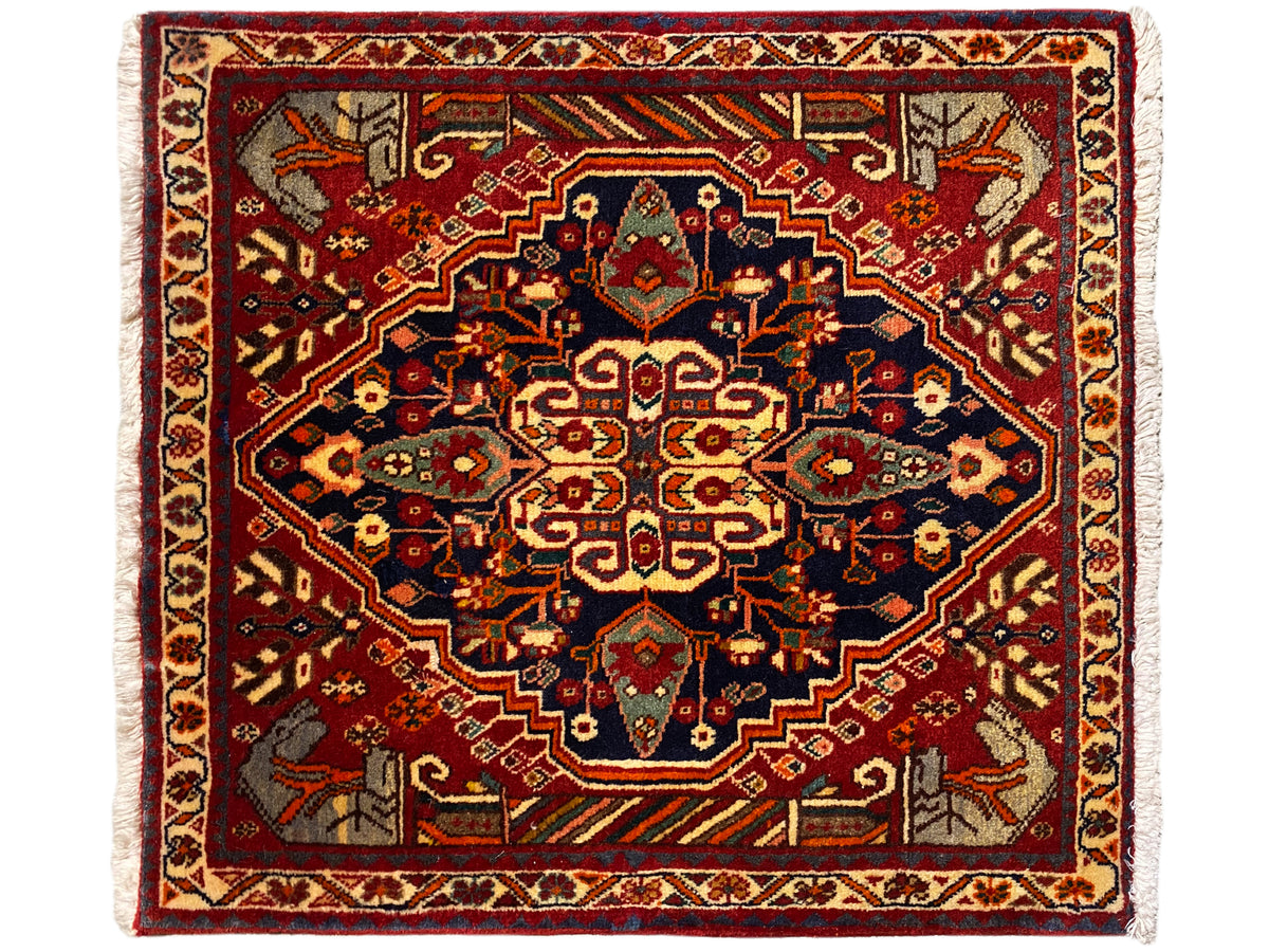 Tapis 65x59 cm à fond rouge, ornements bleu-gris et motif symétrique