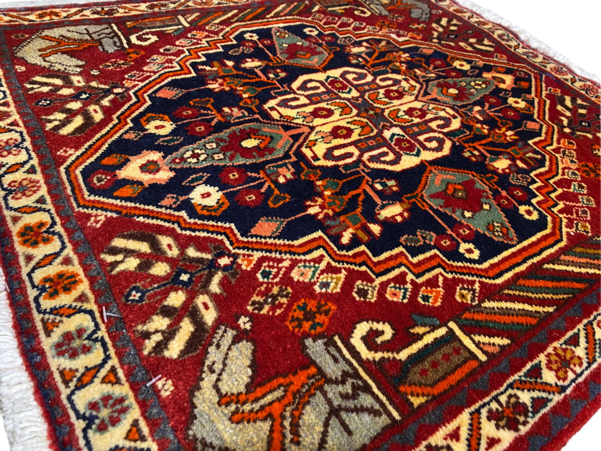 Tapis 65x59 cm en gros plan : champ ornemental central dans des tons bleus, rouges et dorés