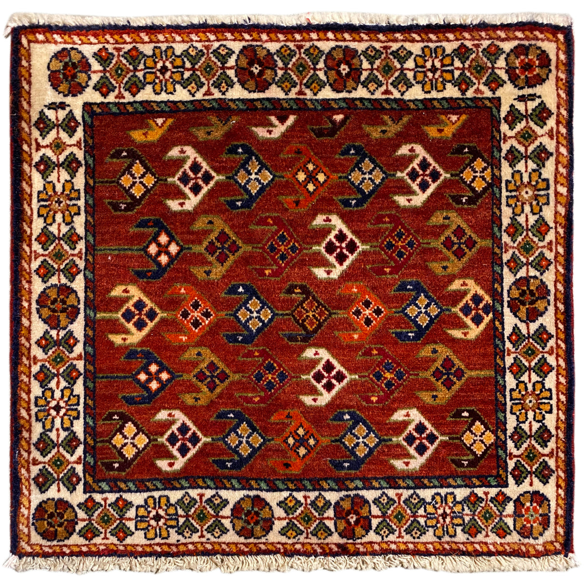 Tapis carré à fond rouge, bordure blanche multicolore et franges
