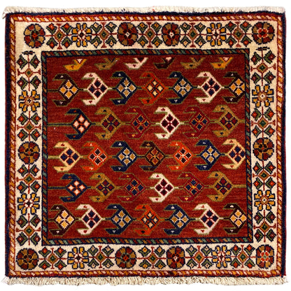 Tapis carré à fond rouge, bordure blanche multicolore et franges