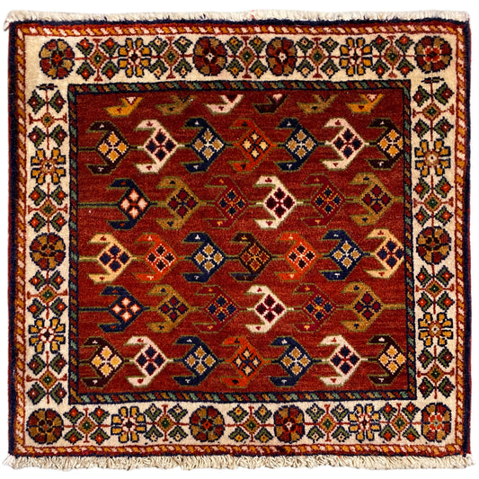 Tapis carré à fond rouge, bordure blanche multicolore et franges