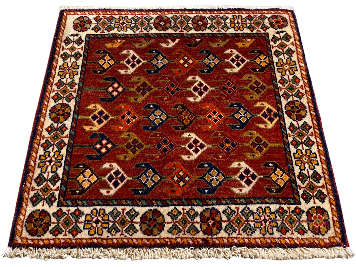 Tapis à fond rouge, motifs multicolores et bordure, franges sur le bord