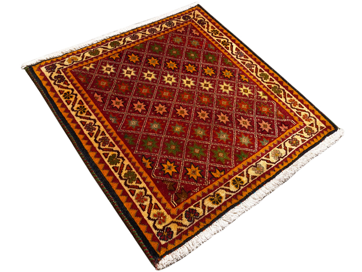 Tapis Poshti, rectangulaire, vue en diagonale : champ intérieur rouge avec motifs étoilés et bordure.