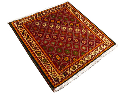 Tapis Poshti, rectangulaire, vue en diagonale : champ intérieur rouge avec motifs étoilés et bordure.