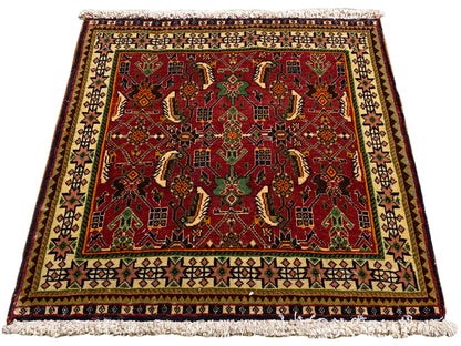 Tapis persan 63x61 cm, vue en biais : motif ornemental rouge sur fond vert et beige.