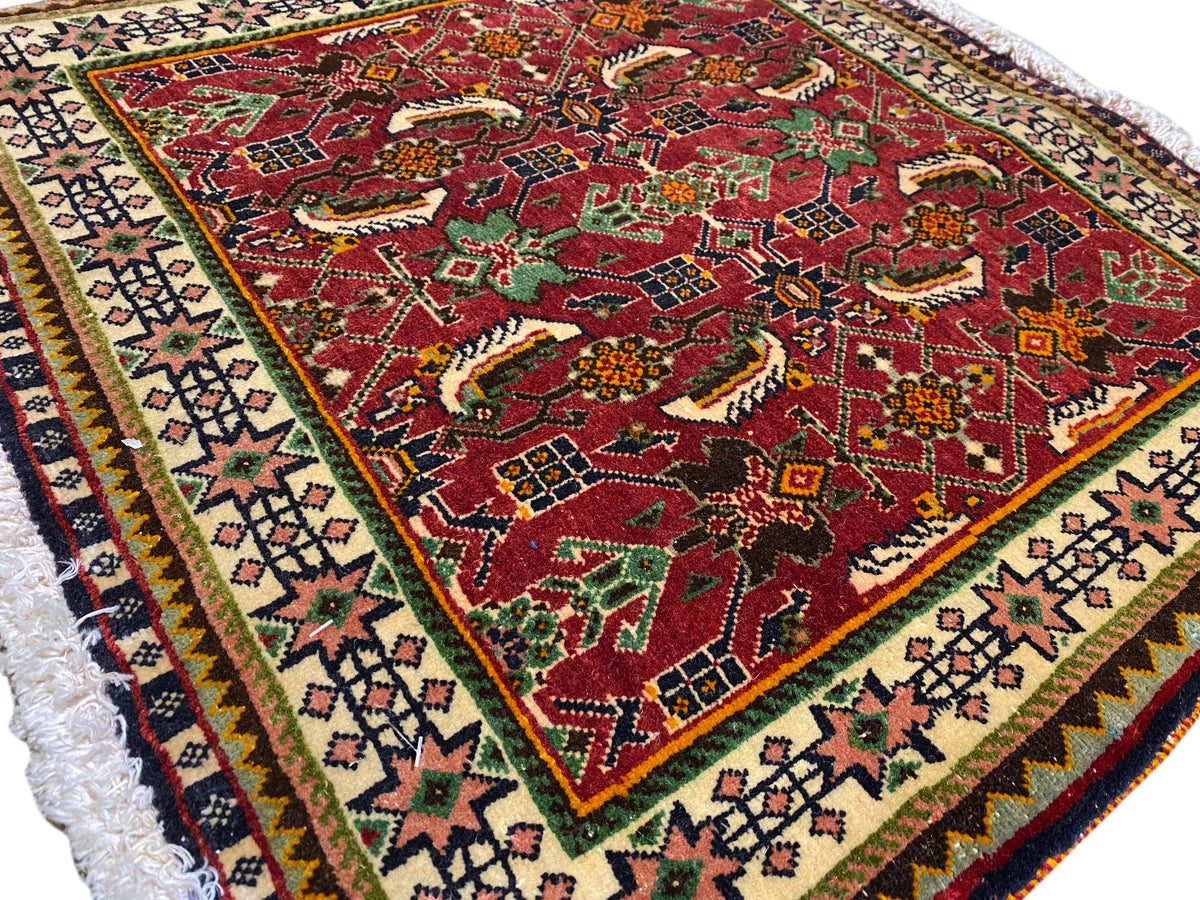 Tapis Poshti 63x61 cm, vue détaillée : motif rouge avec motifs animaliers/ornementaux et bordure.