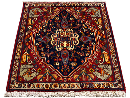 Tapis rouge et bleu foncé avec motif central, forme rectangulaire et franges