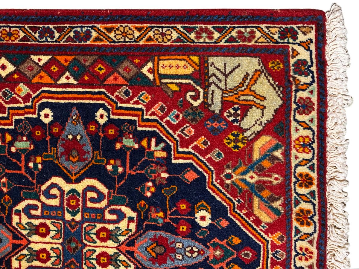 Gros plan sur le bord du tapis avec un motif ornemental bleu, des détails rouges et des franges