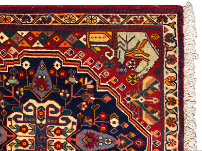 Gros plan sur le bord du tapis avec un motif ornemental bleu, des détails rouges et des franges