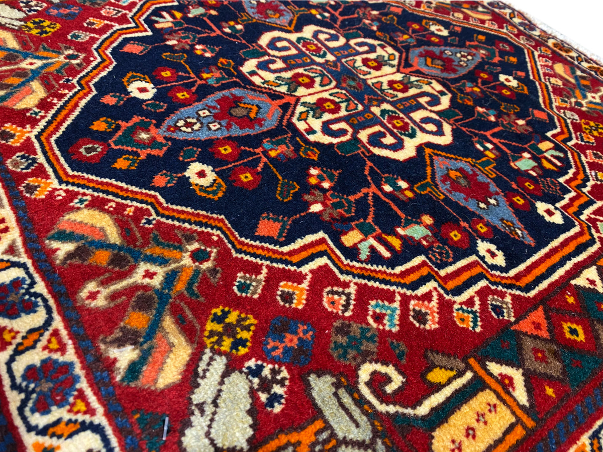 Gros plan sur un tapis : motif bleu avec des ornements rouges et jaunes, texture tissée