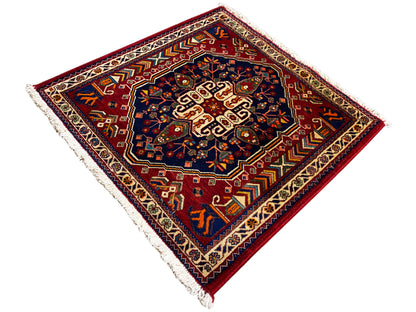 Tapis 63x60 cm vu en diagonale : centre bleu foncé, bord rouge, franges