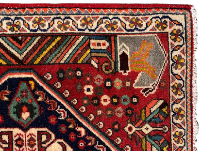 Vue détaillée : tapis rouge aux motifs ornementaux, bordure multicolore et franges