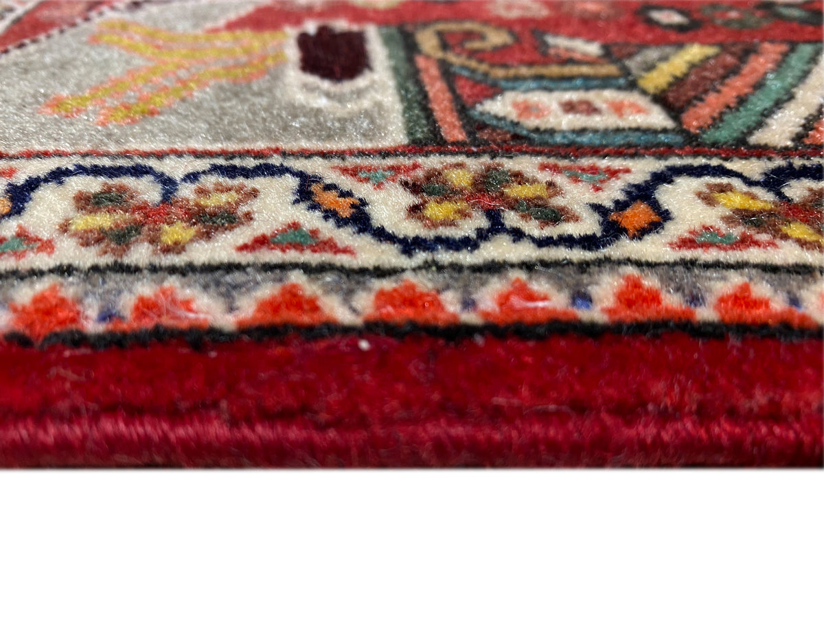 Gros plan : bord de tapis à franges, liseré rouge et motif ornemental dense