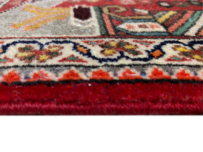 Gros plan : bord de tapis à franges, liseré rouge et motif ornemental dense