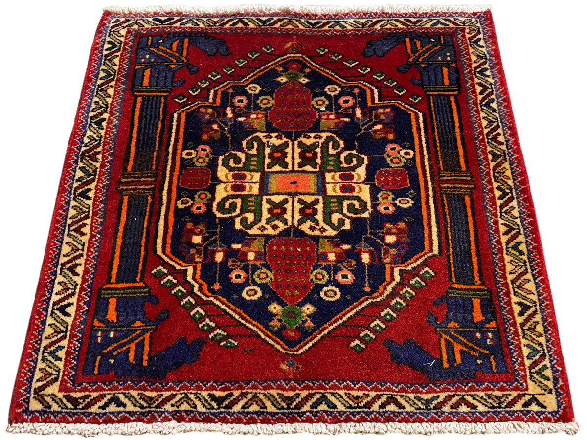 Tapis Poshti 66x62 cm posé à plat : médaillon central rouge orné de motifs géométriques.