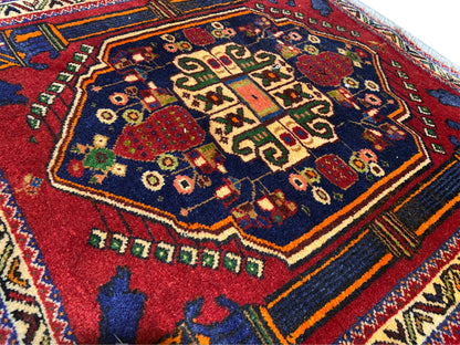 Tapis Poshti 66x62 cm Détail : motif central rouge, champ bleu et lignes décoratives colorées.