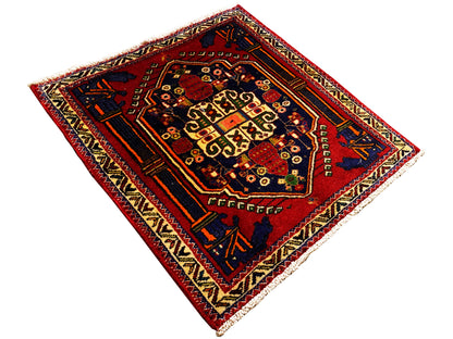Tapis Poshti de 66x62 cm déployé : champ intérieur rouge avec motif géométrique et motifs d’angle.