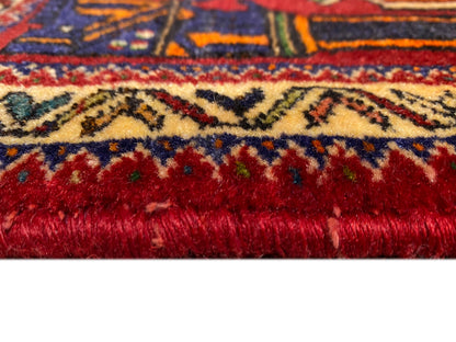 Tapis Poshti 66x62 cm Détail du bord : velours rouge dense avec bordure colorée.