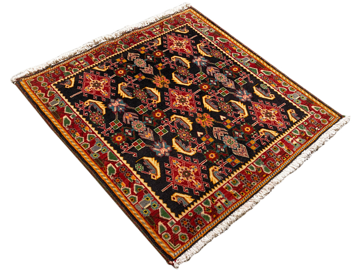 Tapis à motif losanges, noir avec des nuances de rouge, d’orange, de jaune et de vert, bordé en finition