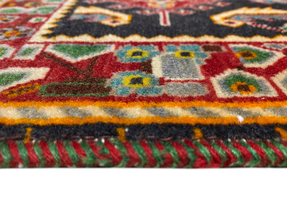 Tapis avec une bande de bordure colorée et des franges, rouge-jaune-vert sur fond noir