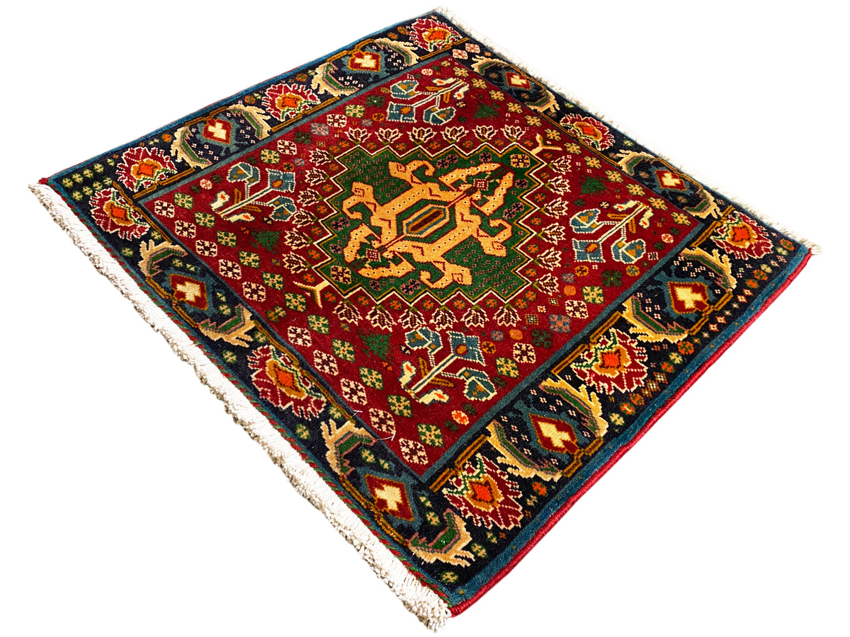 Tapis rectangulaire (67x66 cm) avec un centre rouge, une bordure sombre et des ornements multicolores, franges