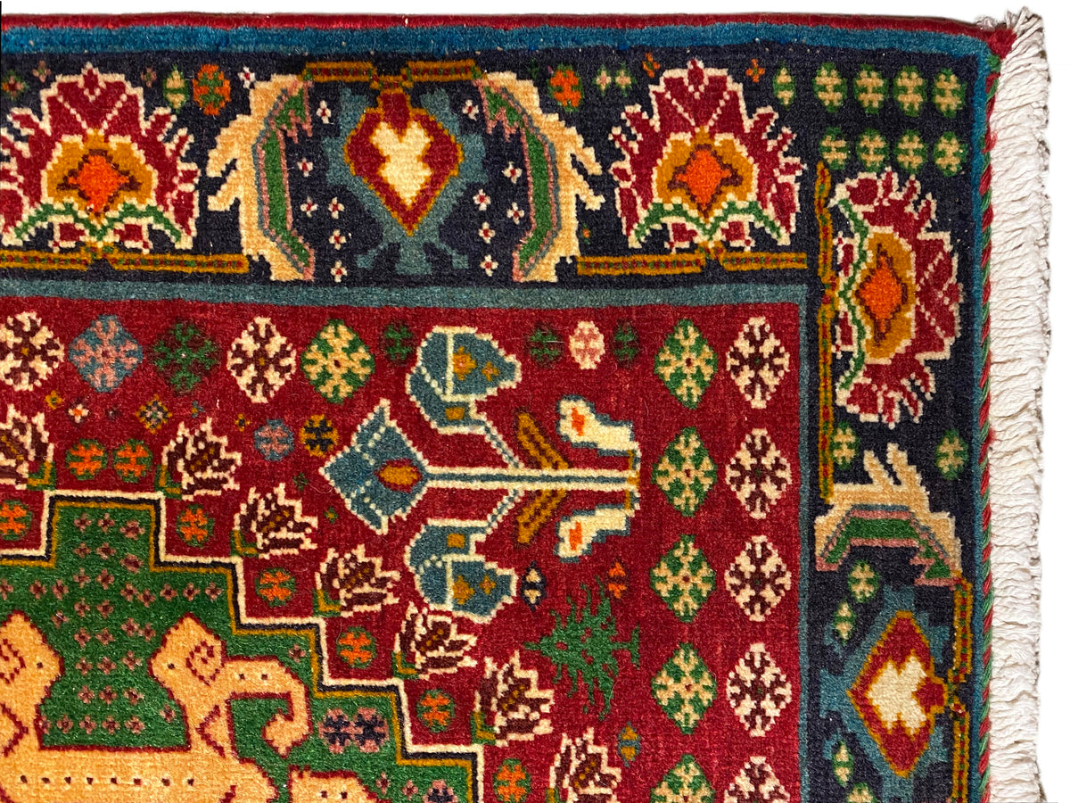 Tapis en gros plan : ornements colorés sur fond sombre, motifs rouges et verts, bordure tissée