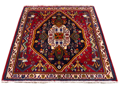 Tapis Poshti (67×67 cm) en vue oblique : bordure, centre rouge, bleu foncé