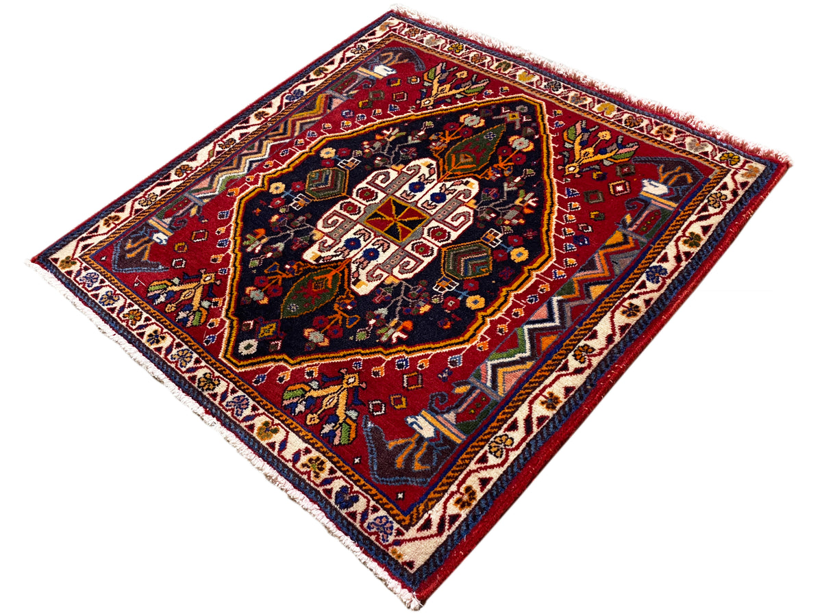 Tapis Poshti (67×67 cm) en diagonale : bordure brun-rouge, champ bleu orné de motifs