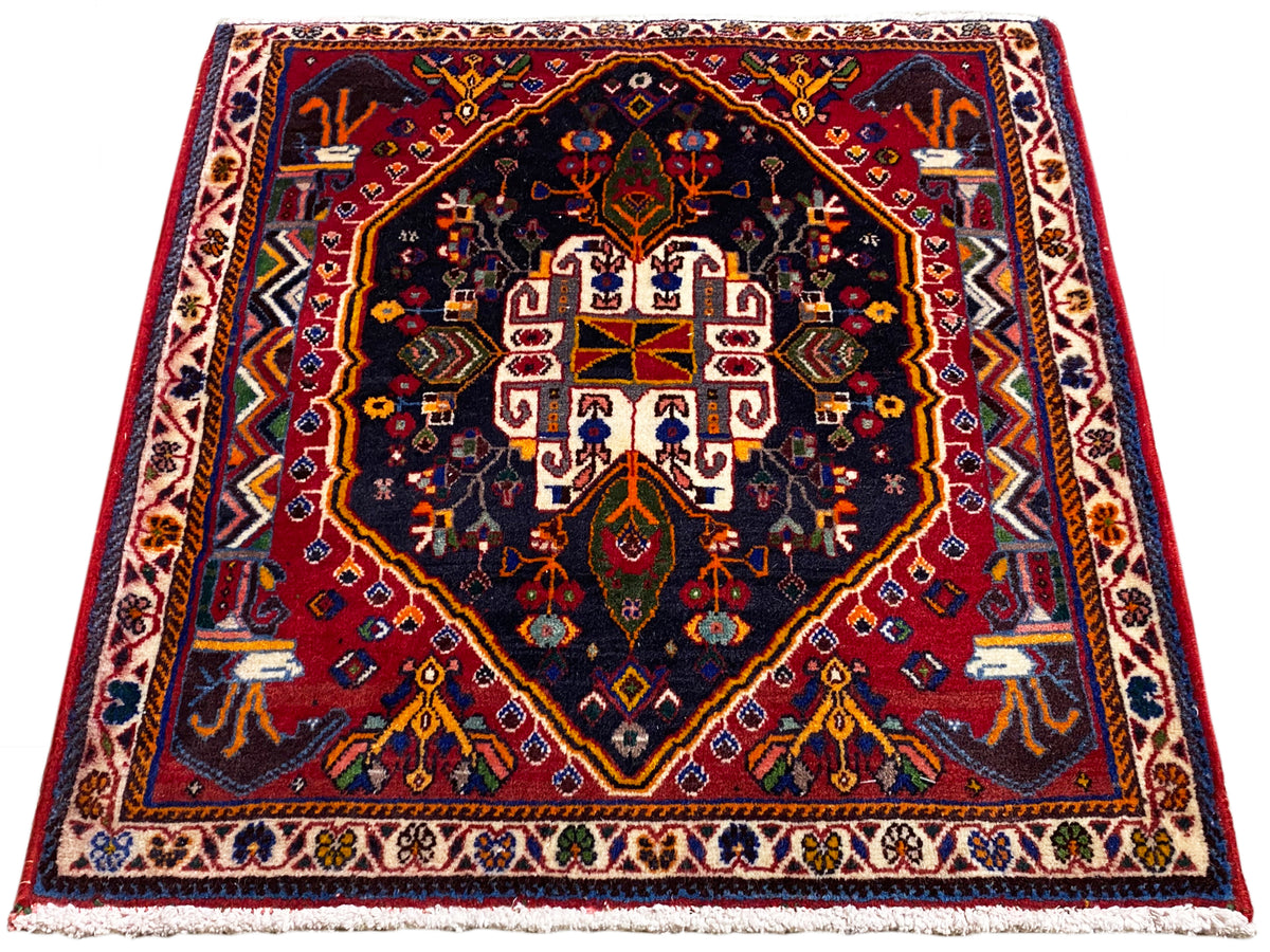 Tapis 70x67 cm à fond bleu foncé, bordure rouge et motif de médaillon symétrique