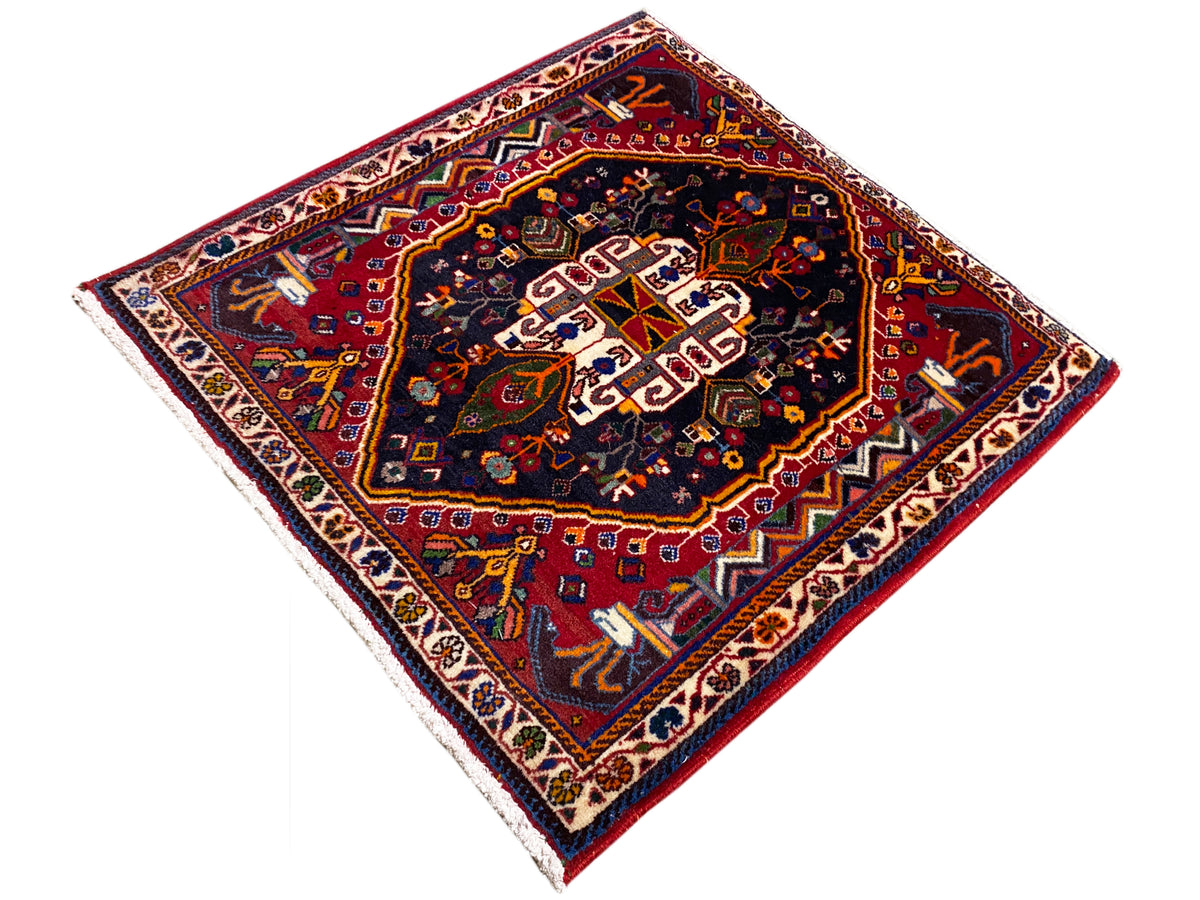 Tapis 70x67 cm : motif ornemental sombre au centre, palette de couleurs rouge et bleue, bordure périphérique