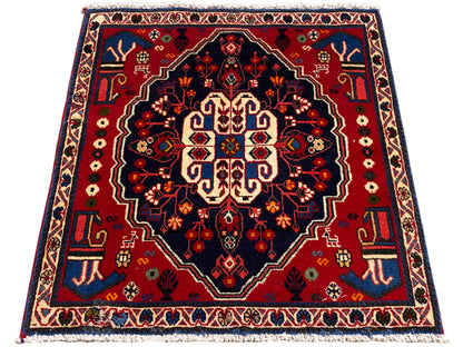Tapis carré à bordure rouge et champ sombre, ornement central stylisé