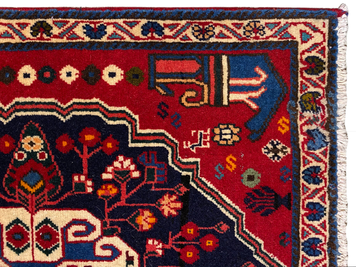 Coin de tapis à fond rouge, symboles colorés et bordure décorative bleue