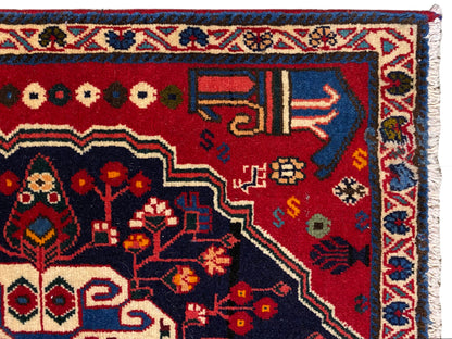 Coin de tapis à fond rouge, symboles colorés et bordure décorative bleue