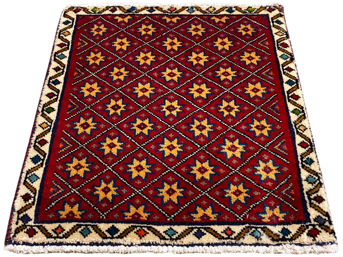 Tapis carré à fond rouge, orné d’étoiles dorées, bleues et noires