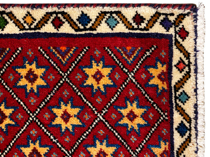Détail du tapis sur le bord : motif d’étoiles rouges avec une bordure blanche à motifs